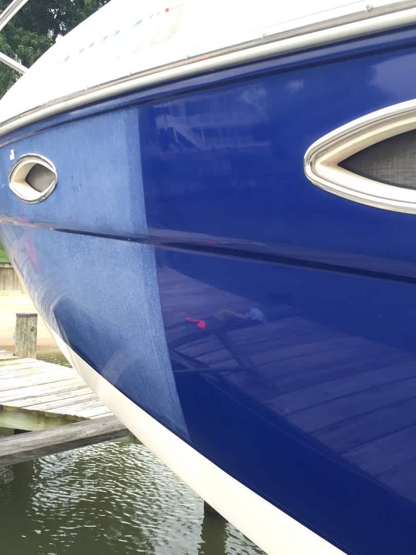 Glossy dark blue boat hull reflecting the dock